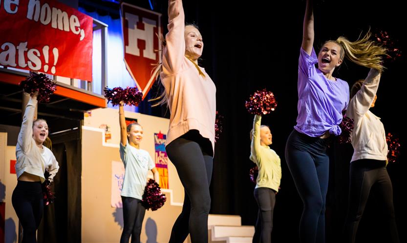 A student in a musical sings onstage